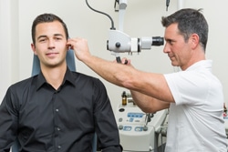 Audiologist examining ear of patient