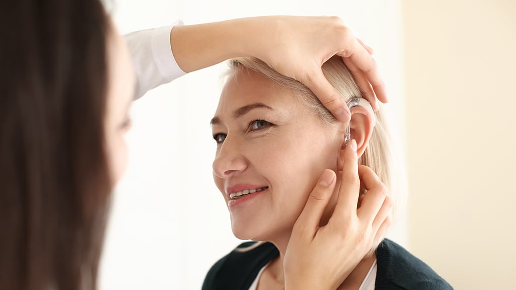 Hearing specialist providing hearing aid maintenance for a senior woman at Bravo Hearing Centre in Etobicoke, representing expert care for adults with hearing loss.