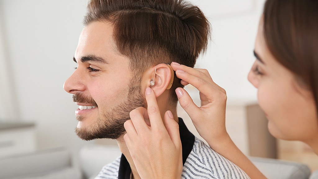 Young man receiving hearing aid maintenance from a specialist at Bravo Hearing Centre in Etobicoke, representing discreet hearing solutions for working professionals.